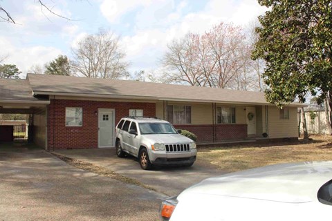 A white car is parked in front of a house.