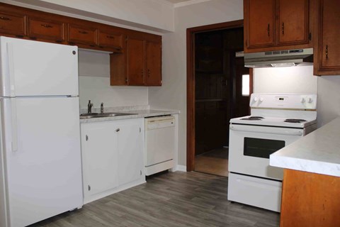 A kitchen with white appliances and wooden cabinets.