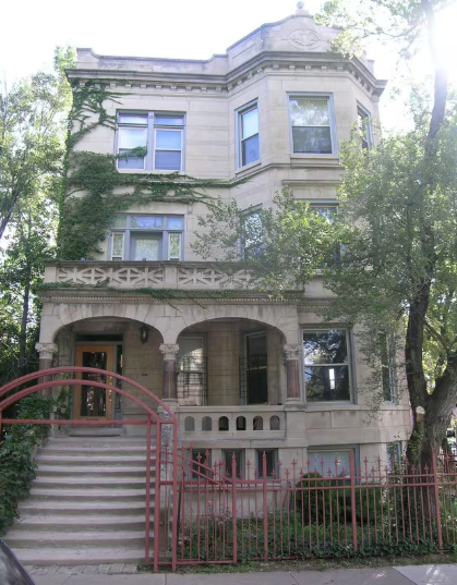 A large, old building with a red gate in front.