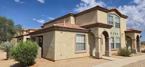 A house with a red tile roof and a brown stucco exterior.