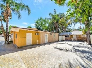 A yellow building with a white door is surrounded by palm trees.