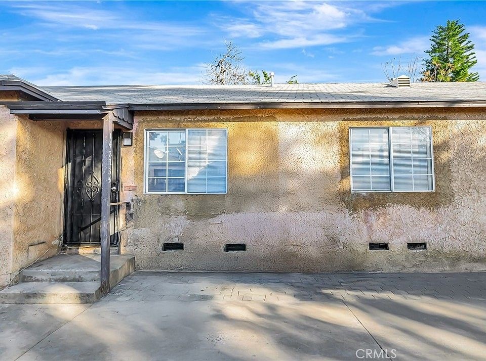 A house with a brown wall and a black door is shown.