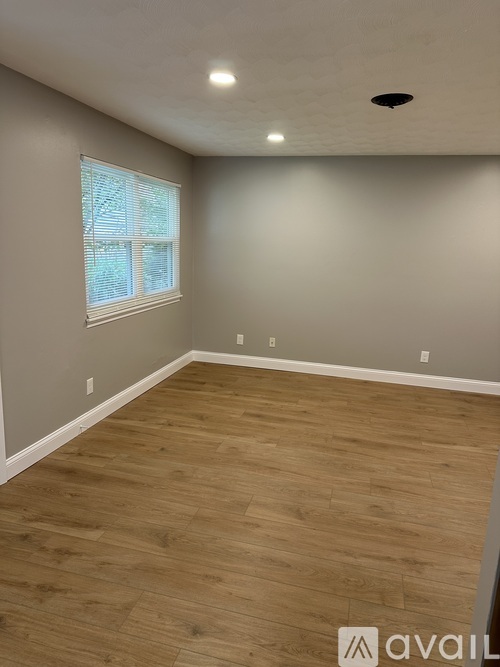 A room with wooden flooring and a window with blinds.