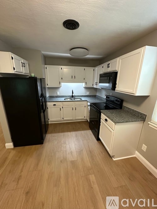 A kitchen with black appliances and white cabinets.