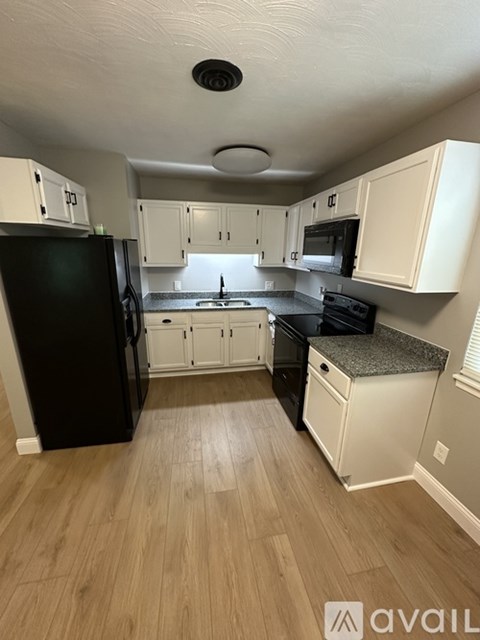 A kitchen with black appliances and white cabinets.
