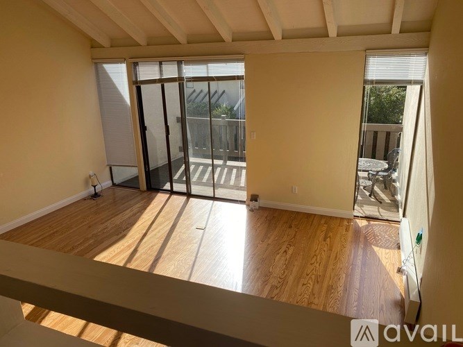 A room with wooden floors and a sliding glass door leading to a balcony.