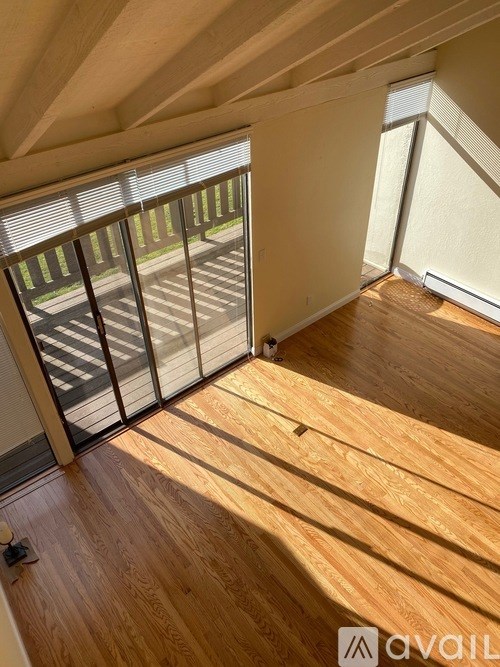 A room with wooden floors and a sliding glass door leading to a balcony.