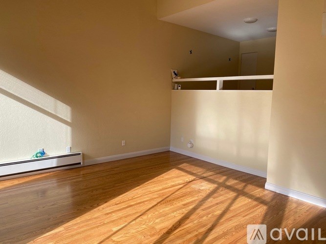 A room with wooden flooring and a window on the left side.