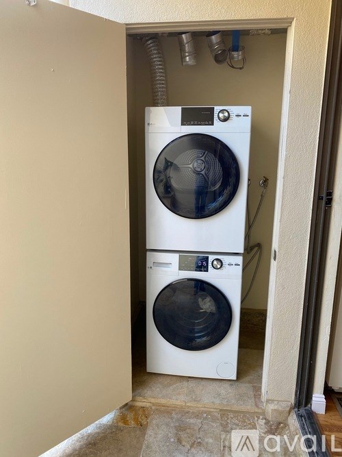 A white front load washing machine is installed in a wall-mounted cabinet.