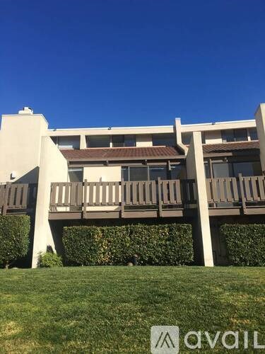 A building with a balcony and a logo on the grass.