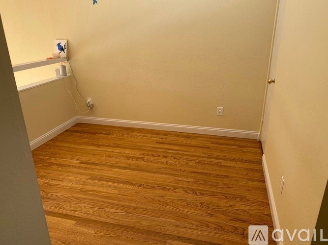 A room with wooden flooring and a white wall.