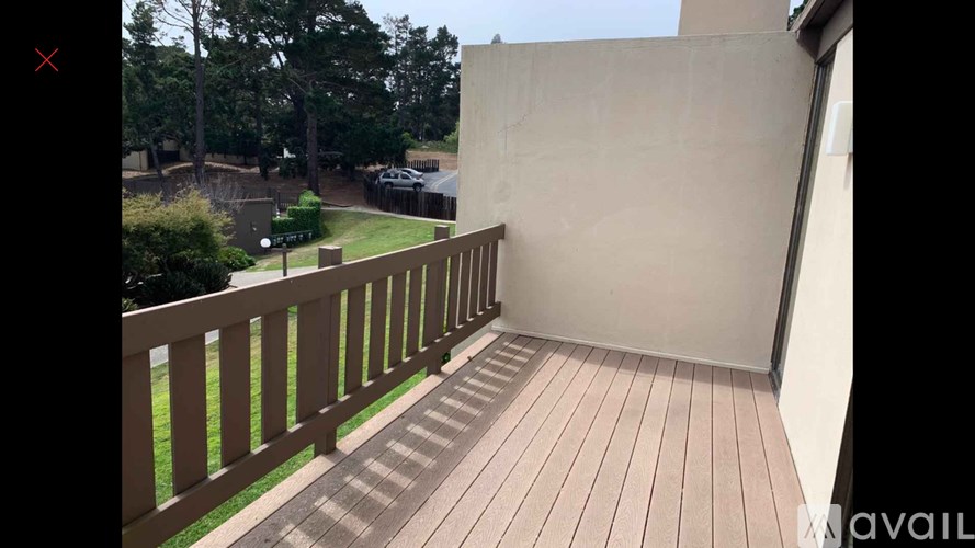 A wooden deck with a railing and a wall in the background.