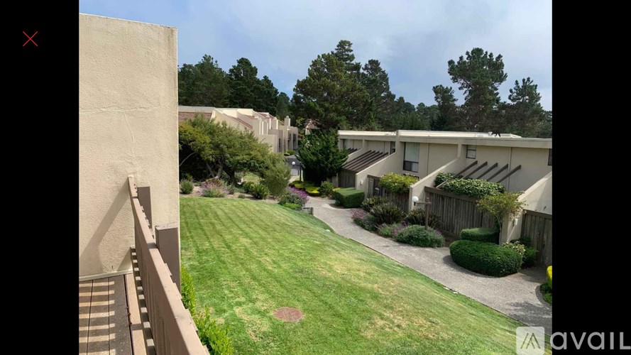A grassy area with a building on the left and a row of houses on the right.