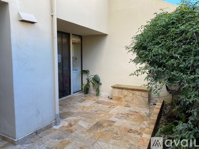 A patio with a tiled floor and a tree in the corner.
