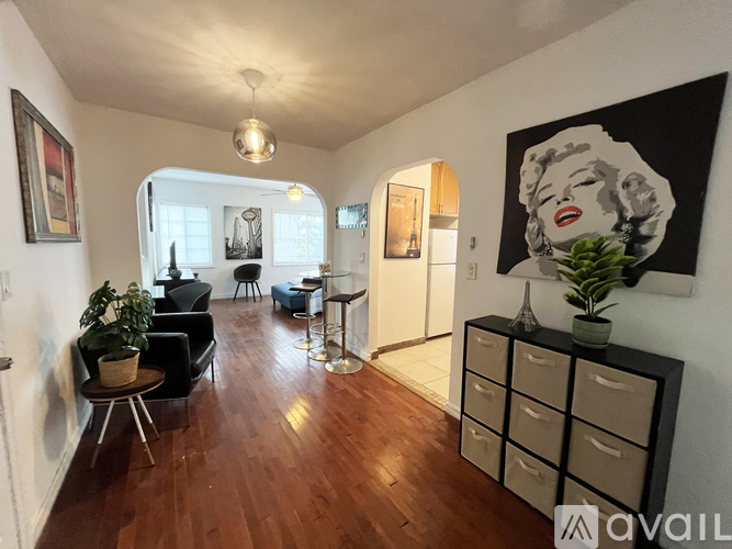 A living room with a wooden floor and a large painting of Marilyn Monroe on the wall.
