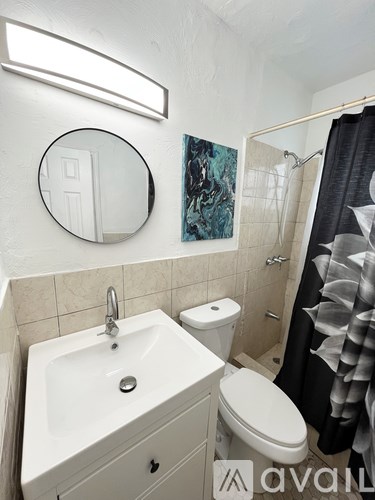 A bathroom with a toilet, sink, mirror and shower.