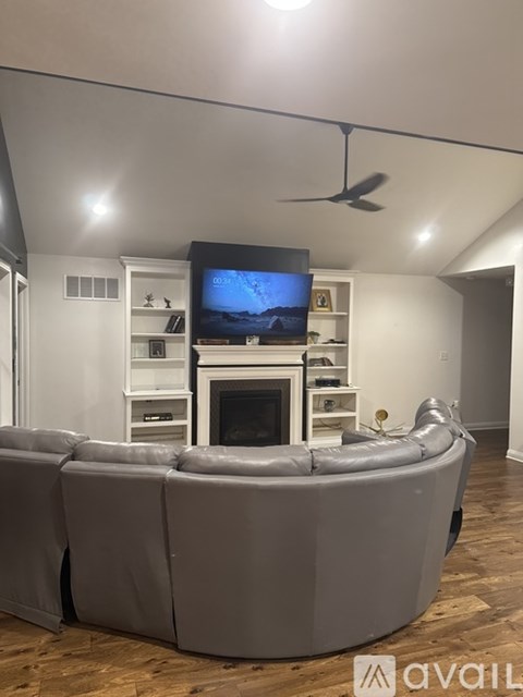 A living room with a grey sofa and a television on a white stand.