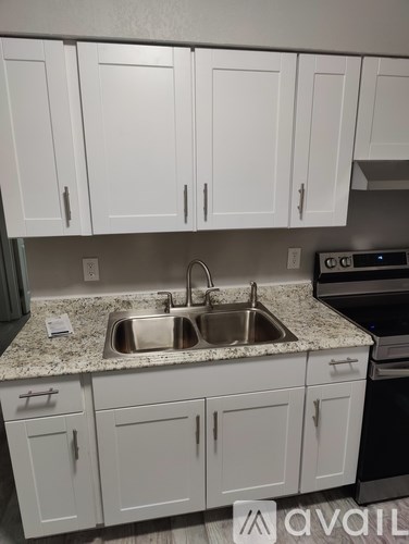 A kitchen with white cabinets and granite countertops.