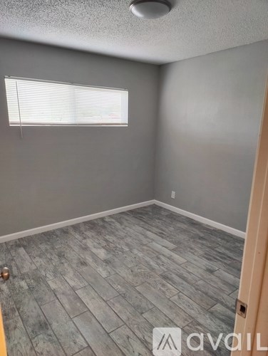A room with a wooden floor and a window with blinds.