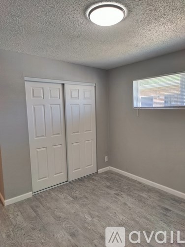 A room with a grey floor and a window with blinds.