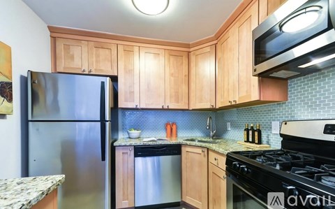 A kitchen with wooden cabinets and a stainless steel refrigerator.