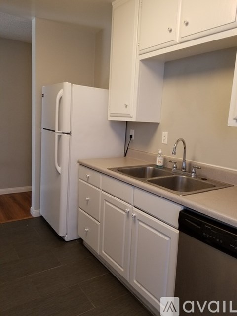 A kitchen with white cabinets and a black dishwasher.