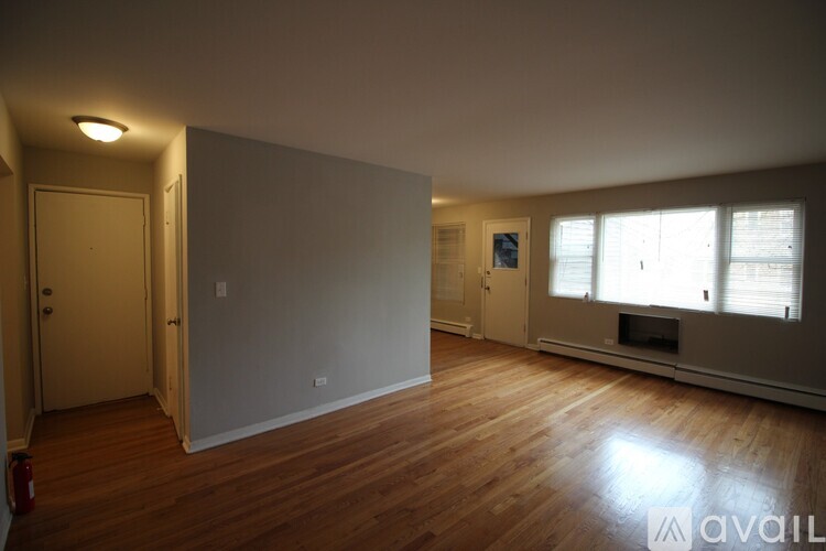 A room with wooden floors and a white wall with a door on the left side.