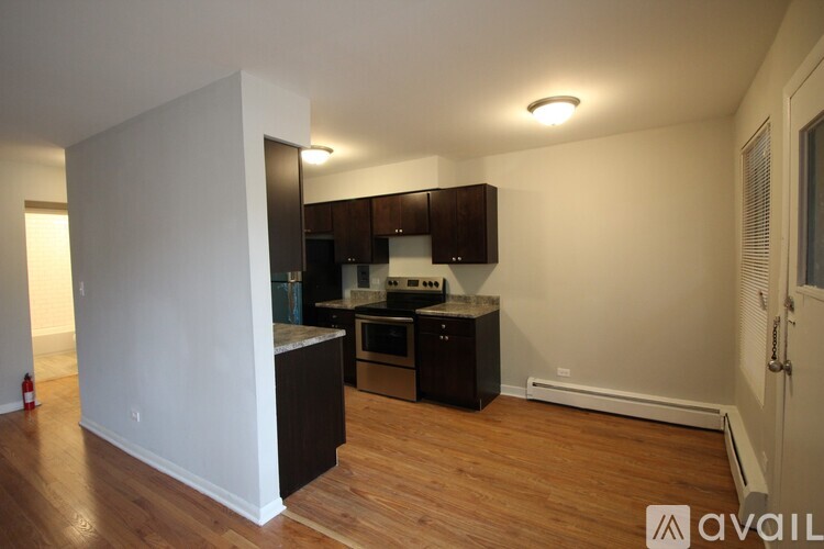 A kitchen with dark wood floors and white walls.