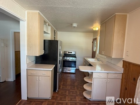 A kitchen with a black fridge and white cabinets.