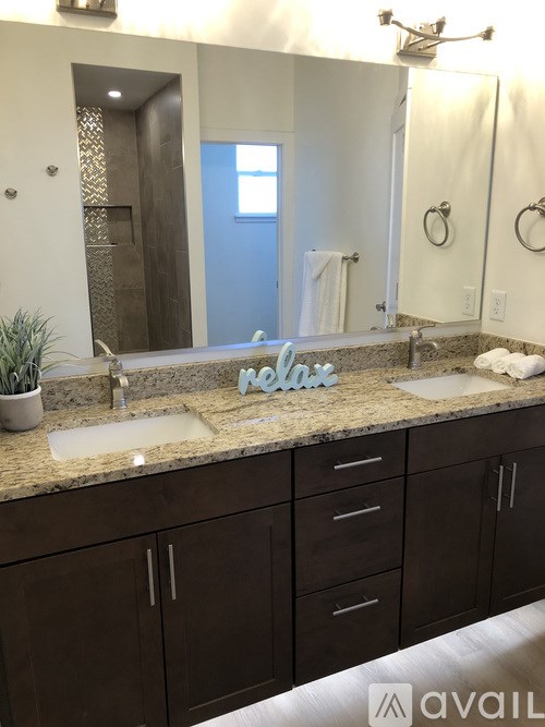 A bathroom with a granite countertop and a mirror above it.