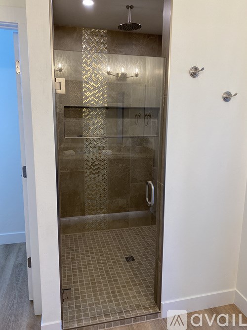 A shower with a glass door and a tiled floor.