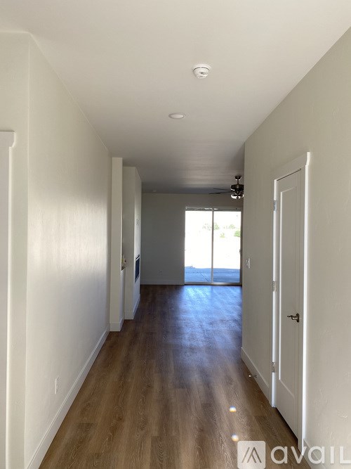 A long hallway with a door on the right and a window on the left.