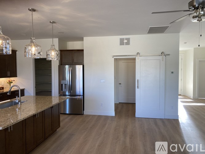 A kitchen with a sink, refrigerator, and cabinets.