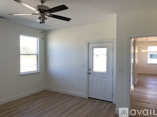 A room with a ceiling fan and a door leading to another room.