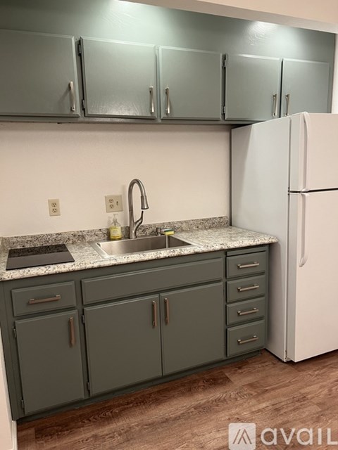 A kitchen with a sink, cabinets, and a refrigerator.