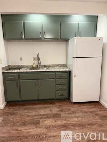 A kitchen with green cabinets and a white refrigerator.