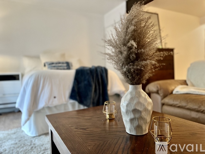 A vase with a feather-like decoration sits on a table in a living room.