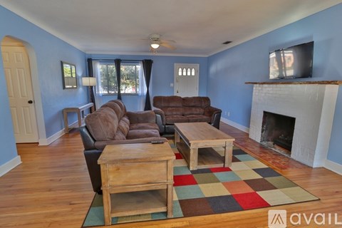 A living room with a fireplace and a television on the wall.