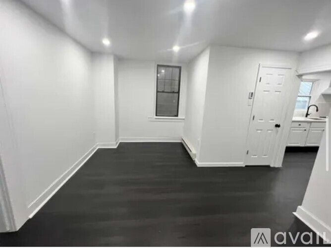 A spacious room with white walls and a black floor.