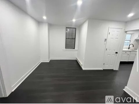 A spacious room with white walls and a black floor.