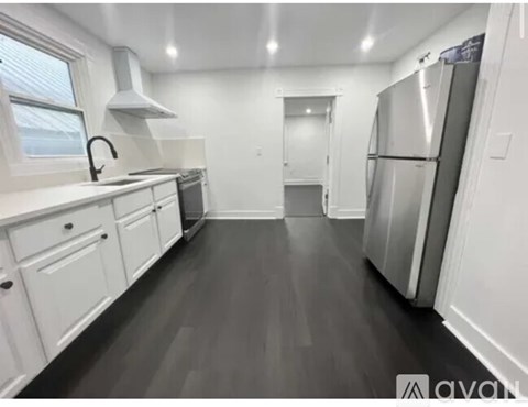 A kitchen with white cabinets and a grey floor.