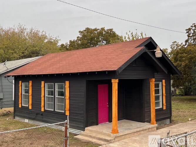 A black house with a red door and orange trim.