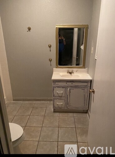 A bathroom with a toilet, sink and mirror.