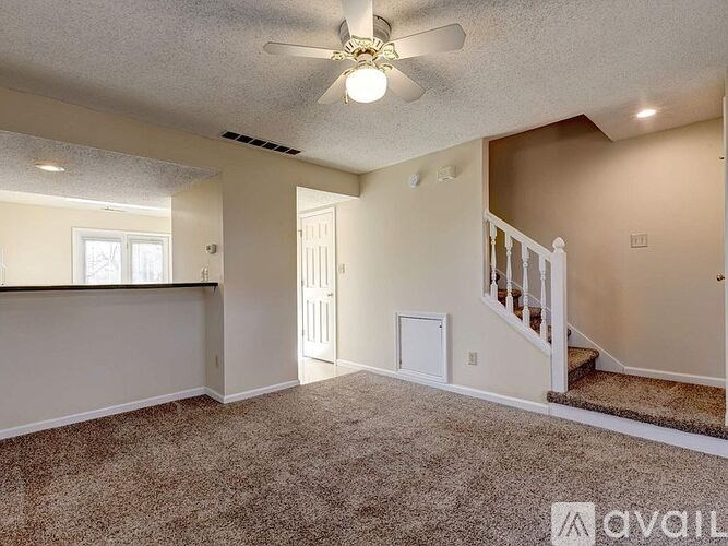 A room with a carpeted floor and a ceiling fan.