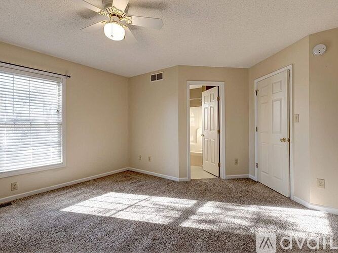 A room with a ceiling fan and carpeted floor.