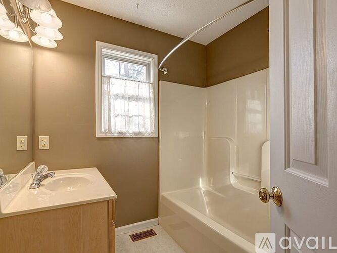 A bathroom with a white sink, a window, and a bathtub.