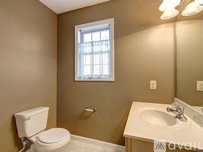 A bathroom with a toilet, sink, and window.