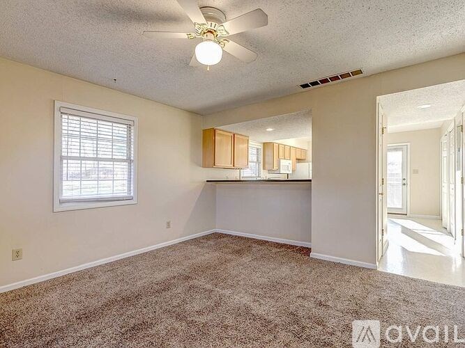 A room with a ceiling fan and carpeted floor.