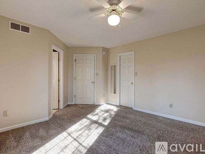 A room with a carpeted floor and a ceiling fan with a light fixture.