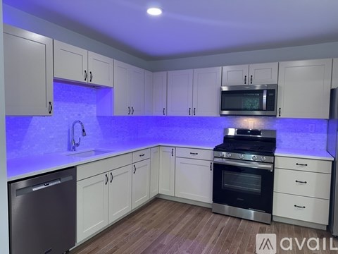 A kitchen with white cabinets and a blue light strip under the counter.